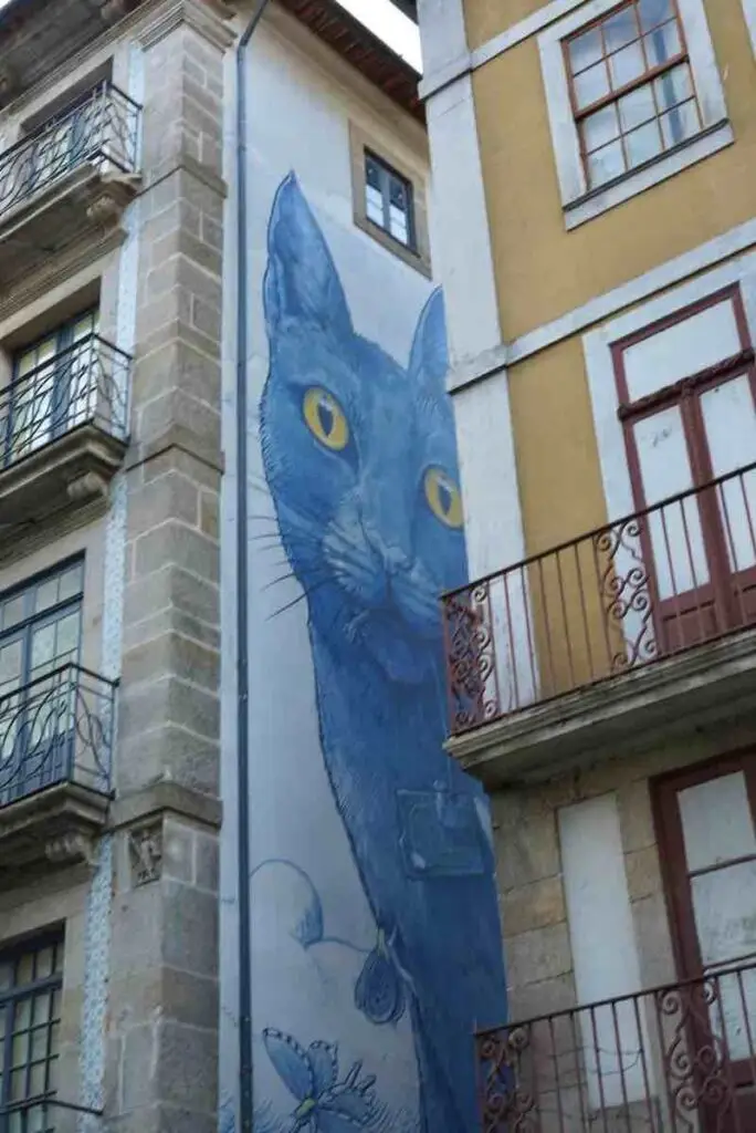 Giant cat street art in between buildings in Lisbon