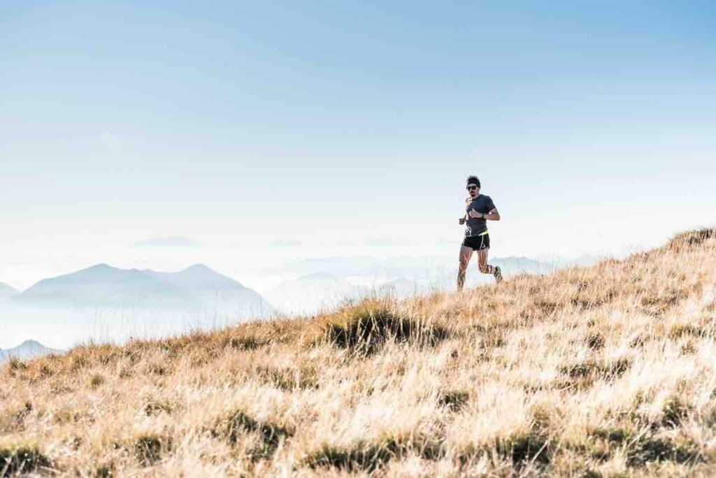 Lone guy hill running against blue sky