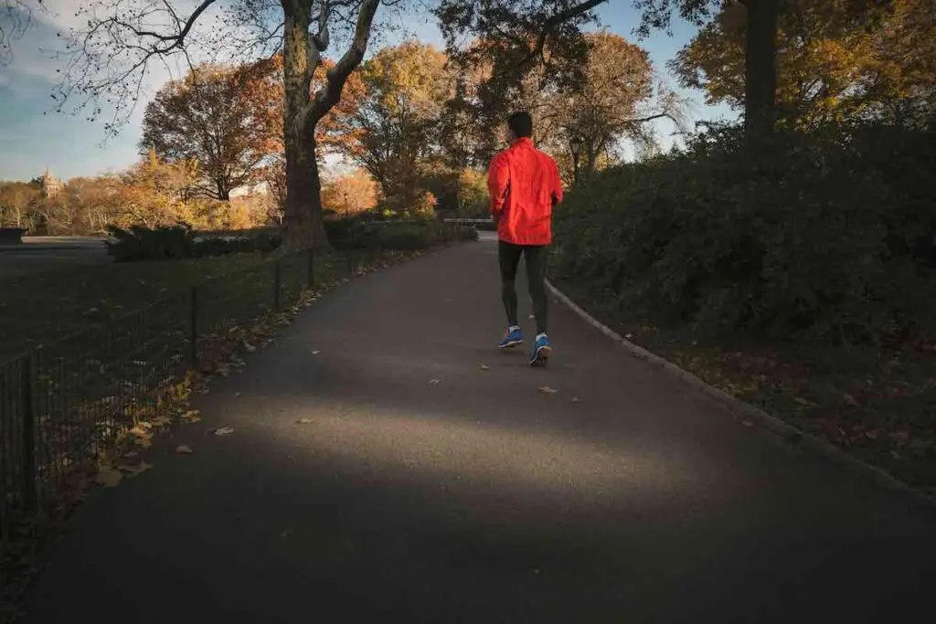 Runner in red running jacket in a park